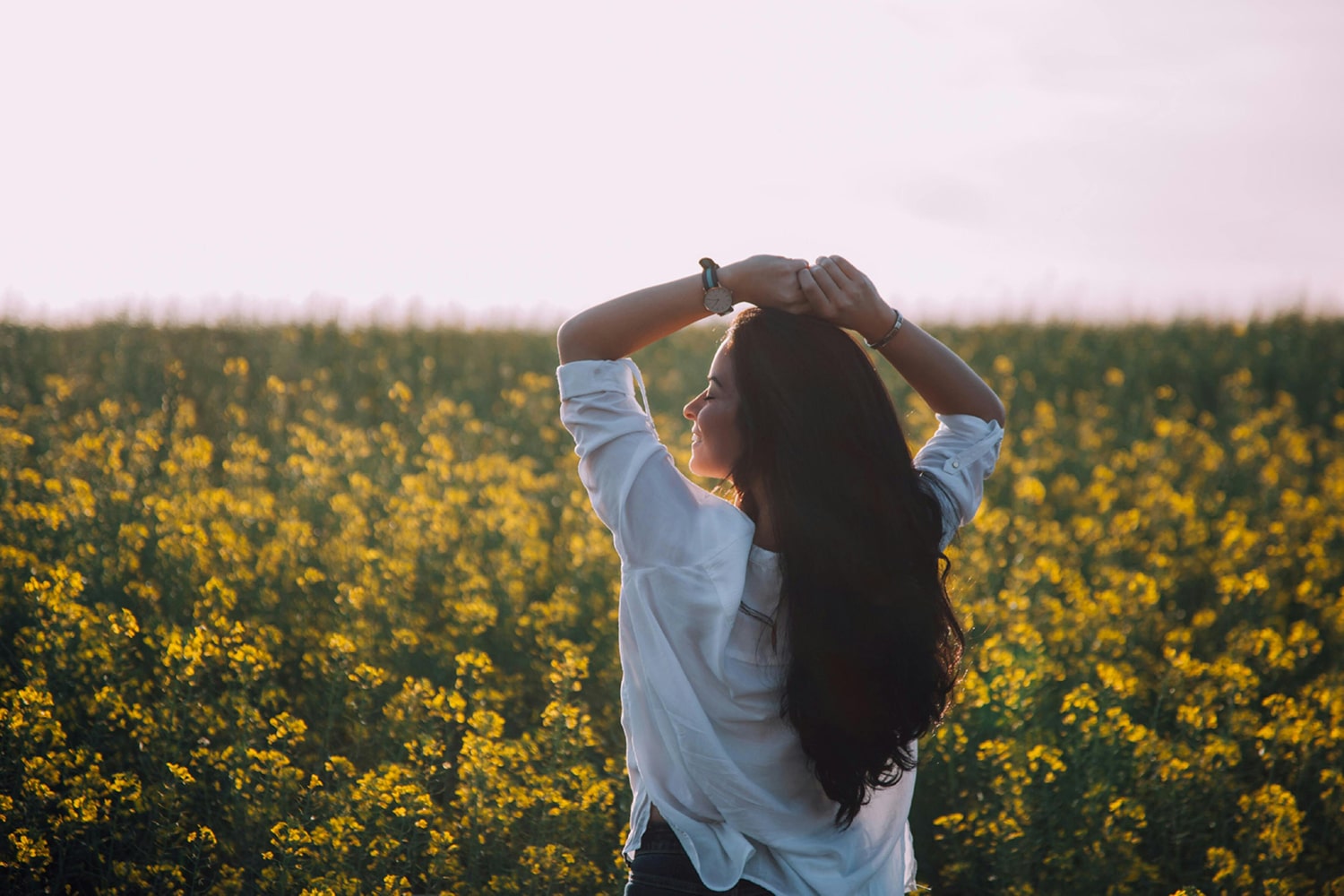 Woman standing confidently in a serene field, symbolizing wellness and the natural benefits of medical cannabis treatments at Homestead Health.