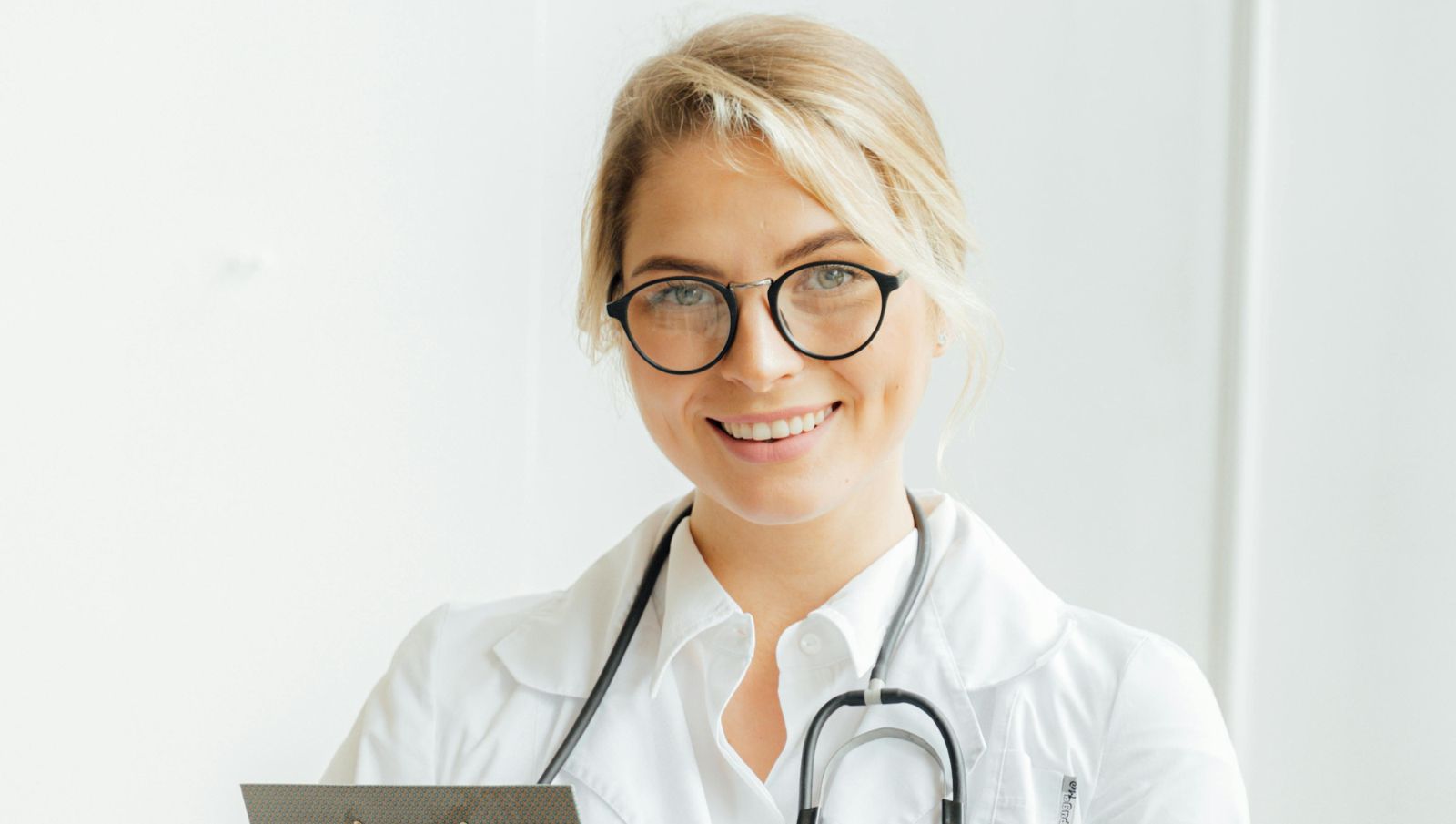 A friendly doctor smiling at the camera in a clinical setting representing accessible medical cannabis care in Montgomery, Alabama.