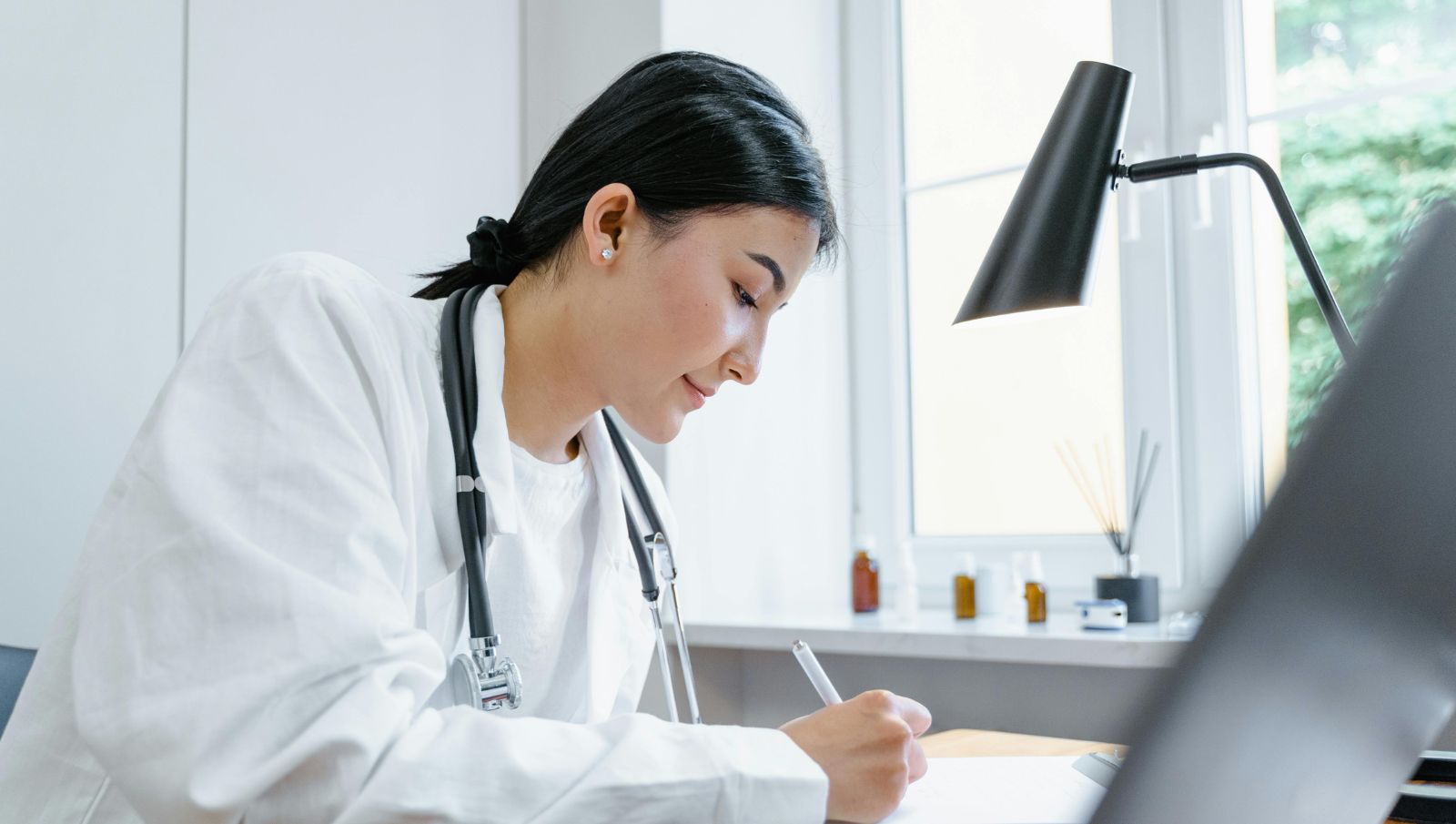 A friendly doctor smiling at the camera in a clinical setting representing accessible medical cannabis care in Talladega, Alabama.