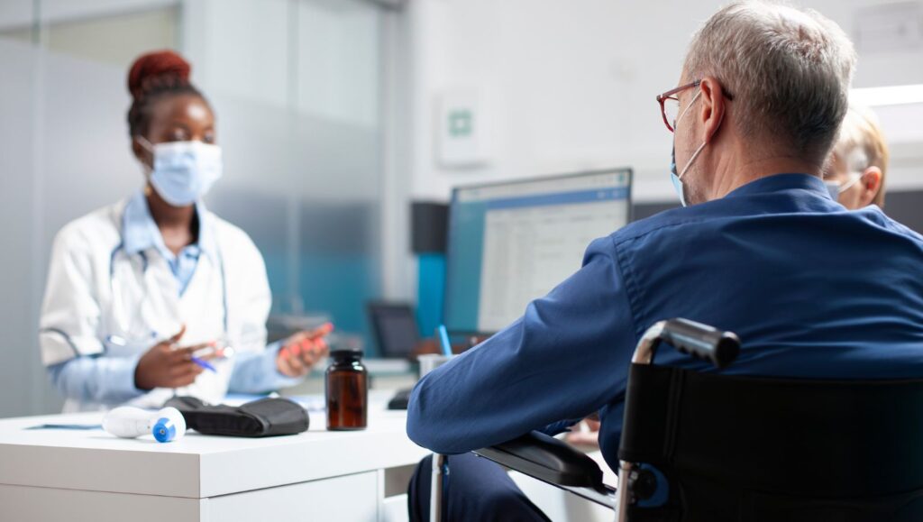 An Alabama medical cannabis patient in a wheelchair discussing the benefits of rosin vs. distillate gummies with his physician.