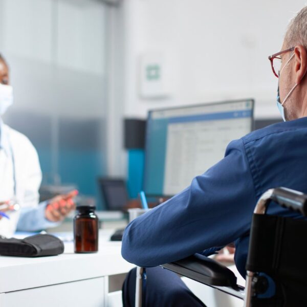 An Alabama medical cannabis patient in a wheelchair discussing the benefits of rosin vs. distillate gummies with his physician.