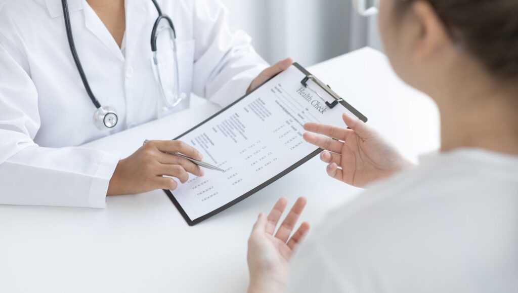 A physician conducting an in-person medical consultation with a patient in an Alabama clinical setting.