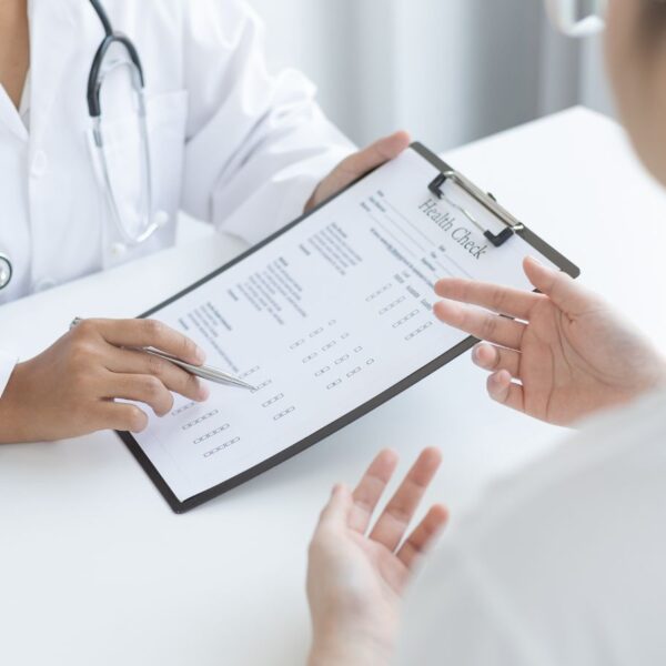 A physician conducting an in-person medical consultation with a patient in an Alabama clinical setting.