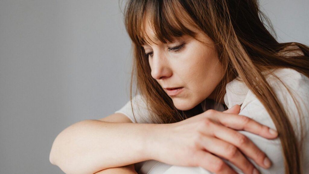 A young female in Alabama sitting alone indoors looking visibly stressed, overwhelmed, and in a depressed state due to a severe panic disorder.