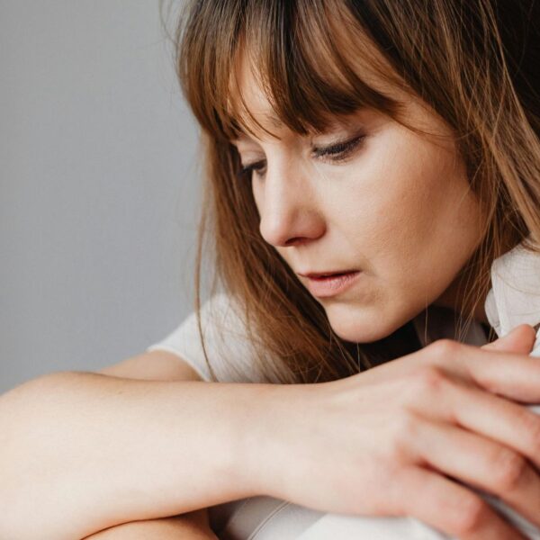 A young female in Alabama sitting alone indoors looking visibly stressed, overwhelmed, and in a depressed state due to a severe panic disorder.