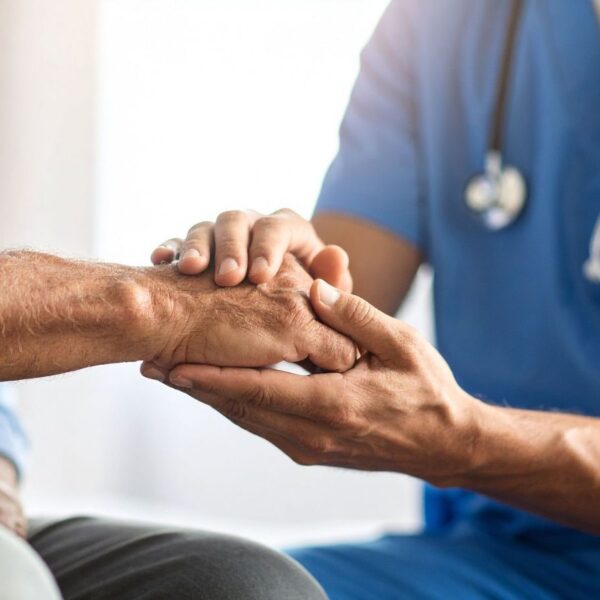 Physician holds an elderly male patient's hand during an in-person Alabama medical cannabis consultation