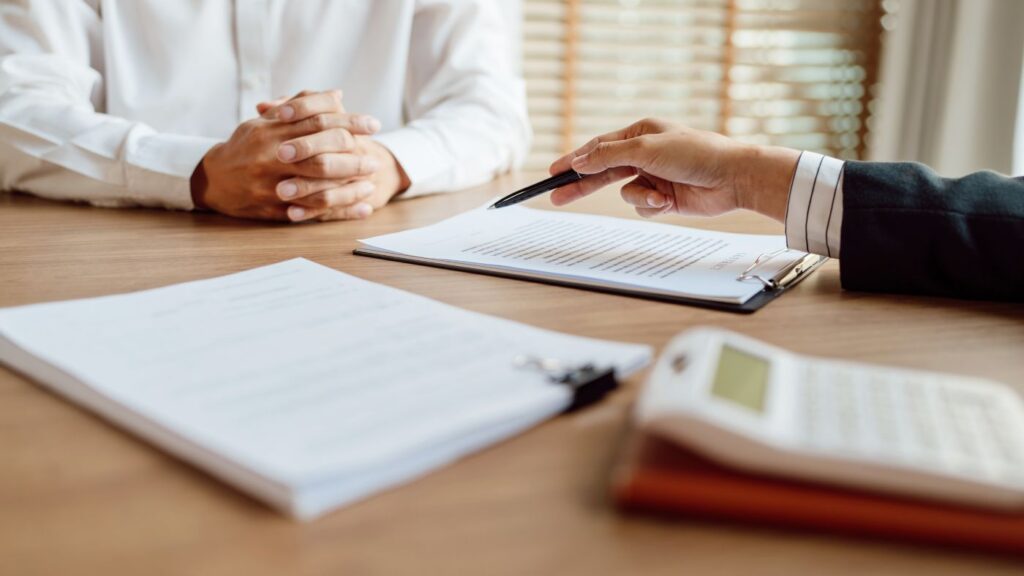 An insurance agent at a desk discussing coverage exclusions and rules with a patient.