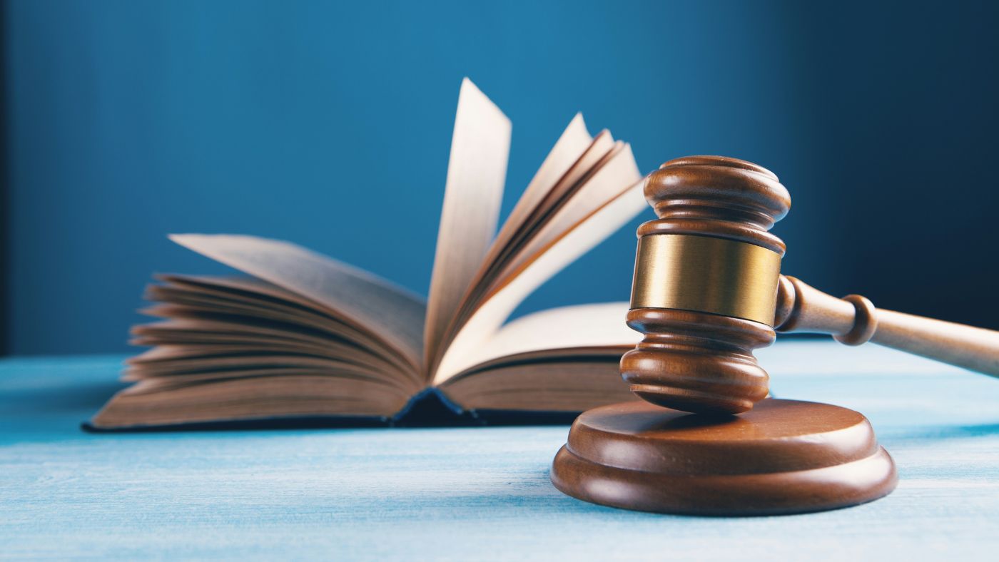 Close-up of a wooden gavel resting on an open legal book, representing administrative sanctions and rulings.